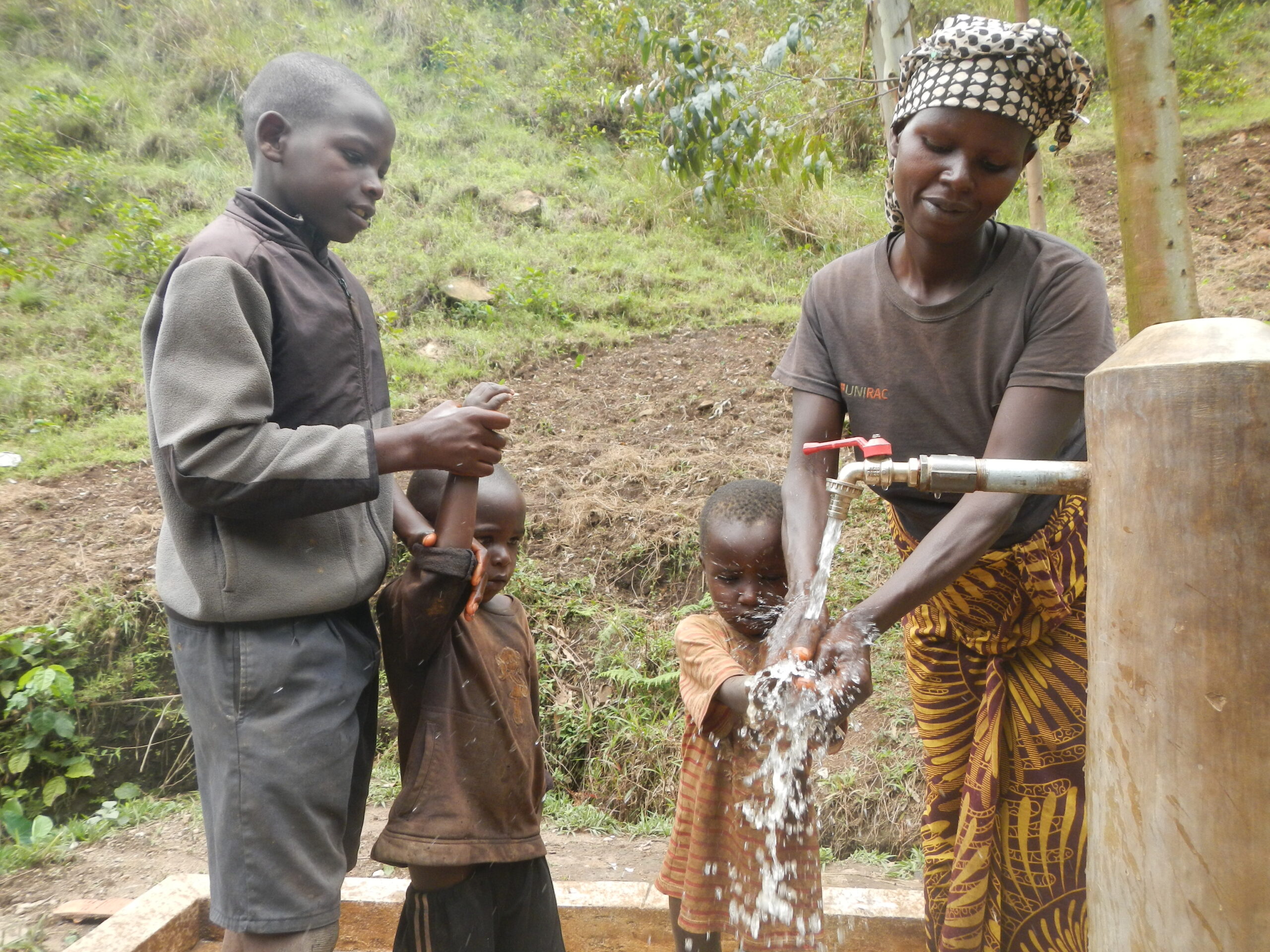 Moeder en kinderen aan een drinkwaterpunt in Burundi.